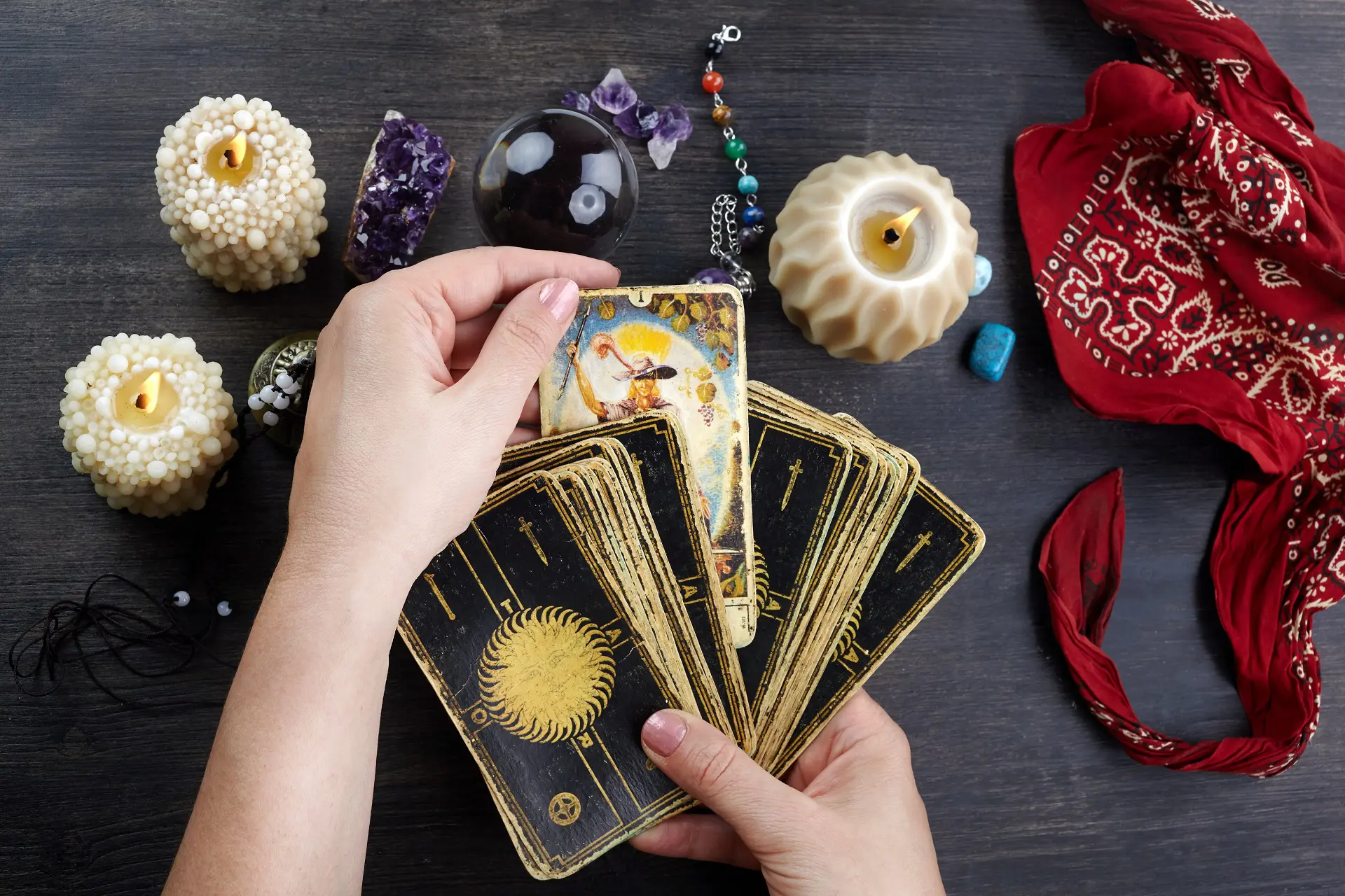Fortune teller female hands and tarot cards on dark wooden table. Divination concept.